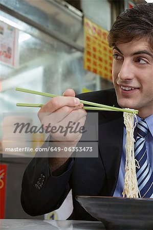 Businessman eating noodles in cafe