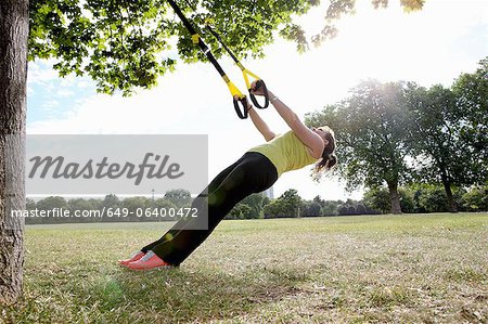 Woman using exercise straps outdoors