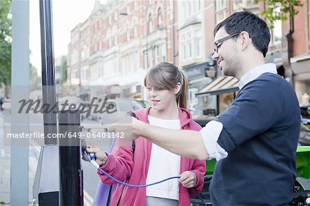 Couple charging electric car on street