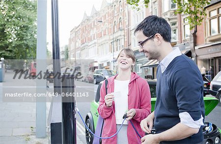 Couple charging electric car on street