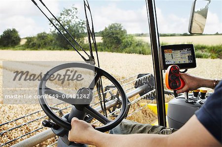 Farmer driving harvester in crop field