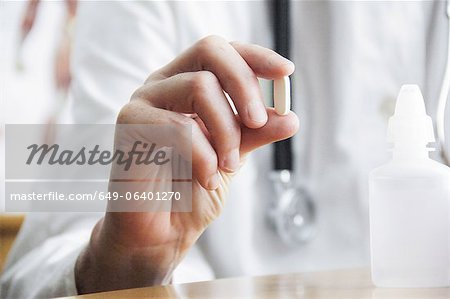 Doctor holding pill in office