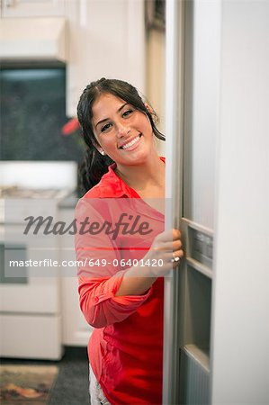 Smiling woman opening fridge door