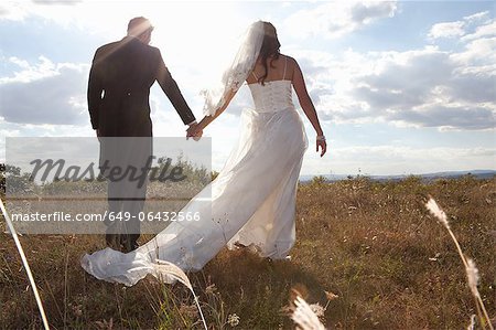 Newlywed couple holding hands in grass