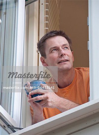 Man with coffee leaning out window