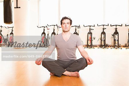 Man meditating on mat at gym