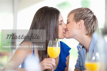 Lesbian couple kissing at table