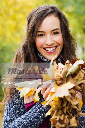 Smiling woman holding autumn leaves