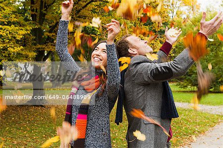 Couple playing in autumn leaves