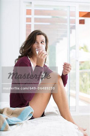 Woman drinking water on bed