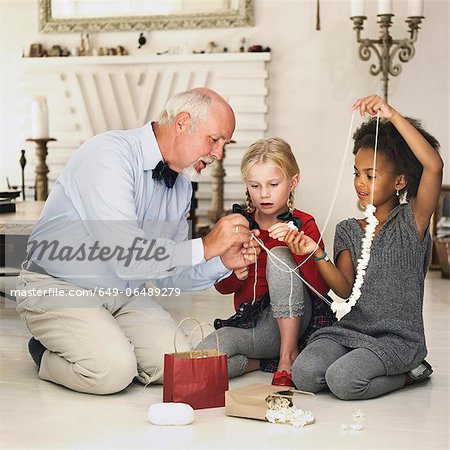 Older man and girls stringing popcorn
