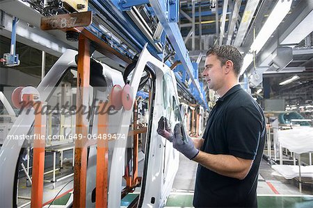 Worker fitting parts in car factory