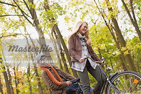 Couple riding bicycle in forest