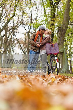 Couple kissing by bicycle in forest