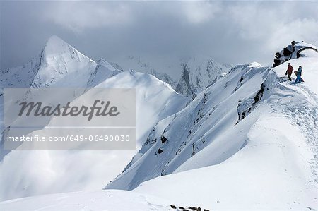 Snowboarders climbing snowy slope