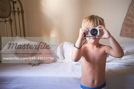 Boy taking picture in bedroom