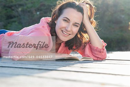 Smiling woman reading on deck