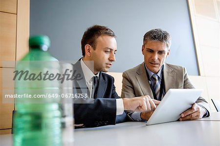 Businessmen using tablet computer at desk
