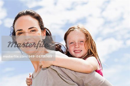 Mother carrying daughter piggyback