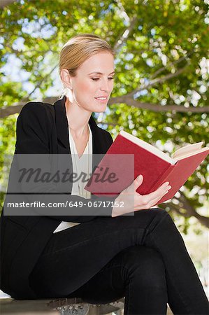 Businesswoman reading book outdoors