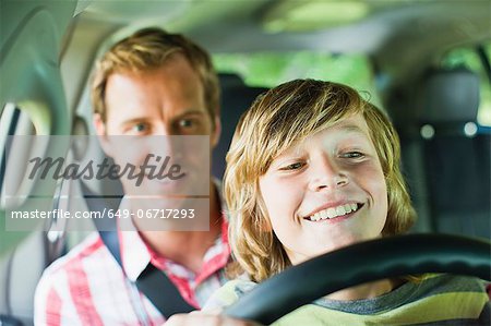 Boy driving car on fathers lap