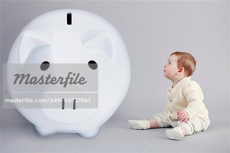 Baby girl examining large piggy bank Baby girl examining large piggy bank