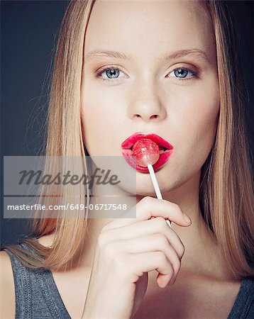 Smiling woman eating lollipop