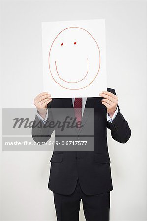 Businessman holding happy face over his face