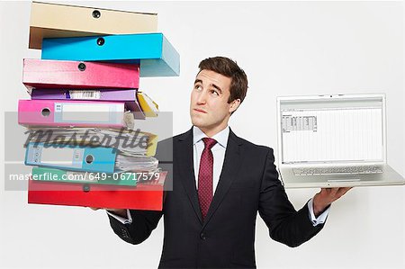 Businessman with stacks of folders and laptop
