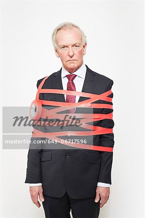 Businessman wrapped in red tape Businessman wrapped in red tape