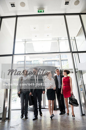 Group of business people talking and entering into glass office building