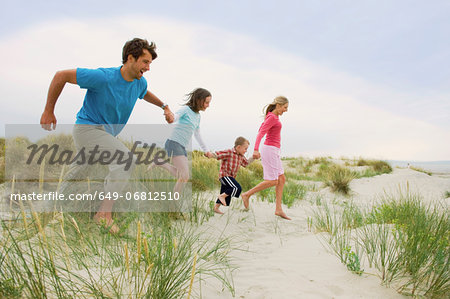 Family holding hands and running at the beach