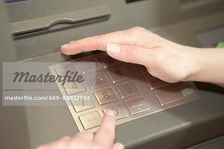 Woman covering keypad when entering PIN in cashpoint