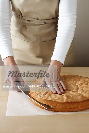 Woman slicing top off sponge cake