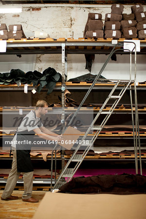 Young man working in leather stockroom