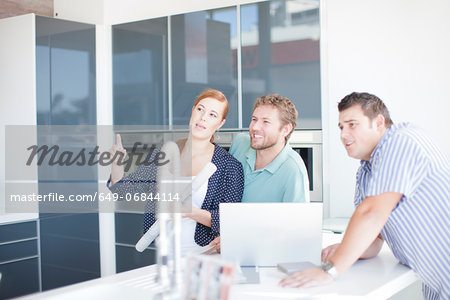 Young couple with salesman in kitchen showroom