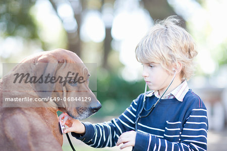Boy using stethoscope on pet dog