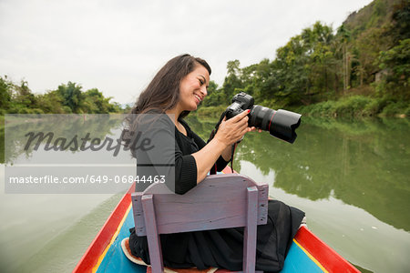 Woman with camera on boat on Nam Song River, Vang Vieng, Laos