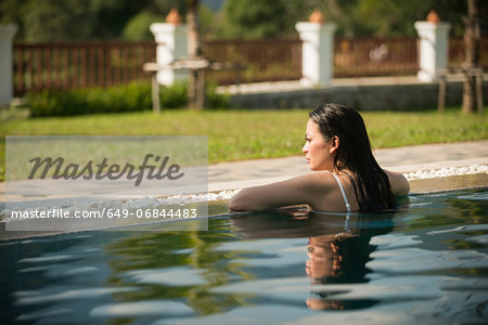 Woman leaning on edge of  swimming pool