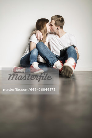 Teenage couple sitting on floor kissing