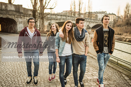 Five teenagers walking together beside river