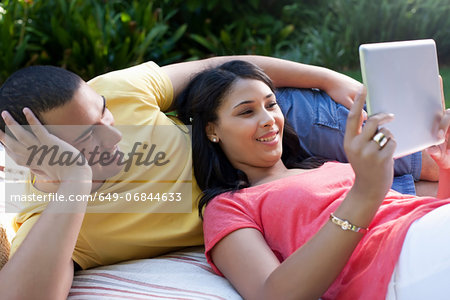 Young couple lying down using digital tablet