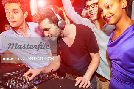 Disc jockey with group of people behind mixing desk