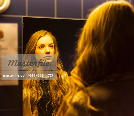 Teenage girl looking at her reflection in mirror