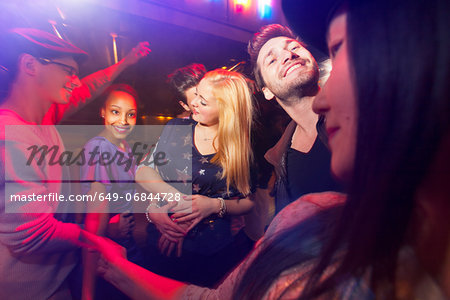 Group of people at party, man kissing woman's neck