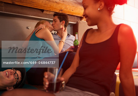 Young couple kissing, friends sitting nearby