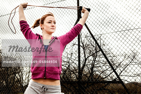 Woman in hoodie stretching pilates rope above head