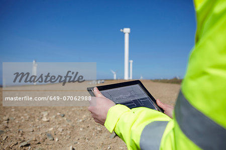 Project manager using digital tablet in front of wind farm