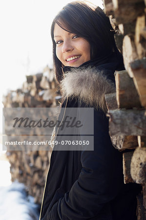 Portrait of young female in front of log pile