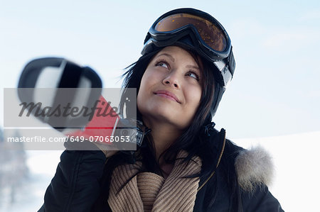 Young female wearing ski goggles and carrying skis